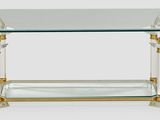 une table en verre avec un piètement doré et un plateau en verre transparent