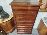 a wooden chest of drawers next to a table with a lamp