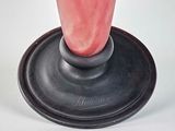 a pink vase with a black base on a white table
