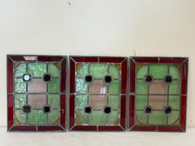 trois vitraux aux encadrements rouges et verts sur un fond blanc