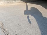 a shadow of a person holding a baseball bat on a sidewalk