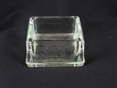 a clear glass box with a lid on a black background
