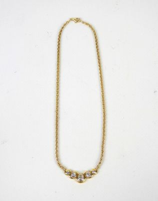 a gold chain necklace with three small white stones on it