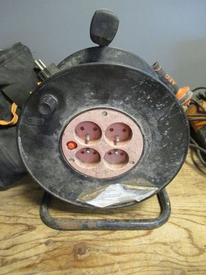 un ventilateur noir posé sur une table, à côté d'une paire de bottes