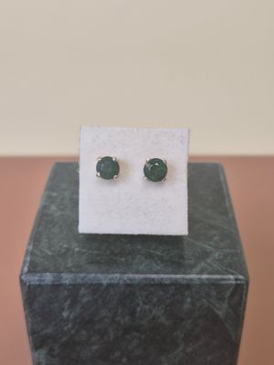 a pair of green stone stud earrings sitting on top of a marble block