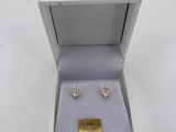 a pair of earrings in a box on a white surface