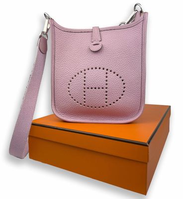 un sac à main rose posé sur une boîte, à côté d'une boîte orange