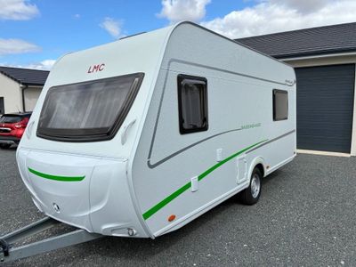 an image of a white caravan parked in front of a garage
