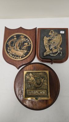 three plaques on a white surface with a wooden plaque in the middle