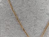a gold plated necklace with a triangle pendant on a mannequin mannequin