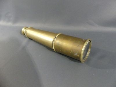 an antique brass telescope on a grey background