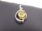 a close up of a yellow sapphire and diamond pendant on a black leather surface