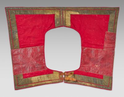 un vieux morceau de tissu rouge et doré, avec un trou carré au milieu