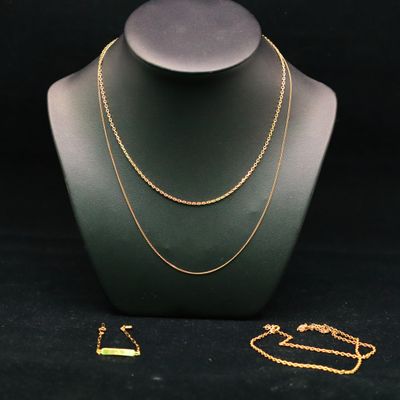 un ensemble composé d'un collier et d'un bracelet en or, posé sur un présentoir pour mannequin