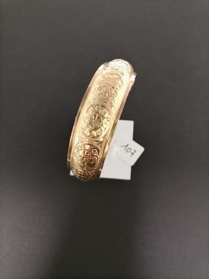 a close up of a gold bracelet on a black surface