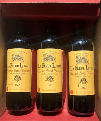 three bottles of red wine in a cardboard box on a table