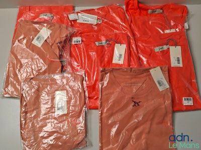 Plusieurs t-shirts orange sont emballés dans des sacs en plastique sur une table