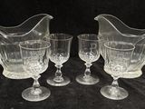 trois pichets en verre transparent et deux verres à vin posés sur une nappe noire