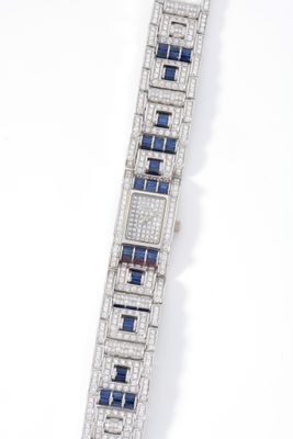 a close up of a diamond and sapphire bracelet on a white surface