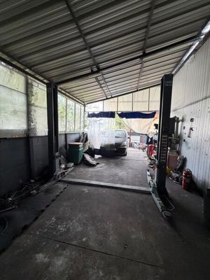 une voiture garée dans un garage, avec un camion en arrière-plan