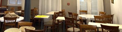 de nombreuses tables et chaises dans un restaurant, recouvertes de nappes blanches