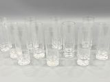 six clear glass vases lined up in a row on a white surface