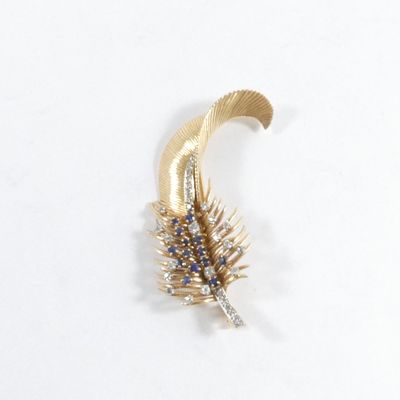 une broche en forme de plume en or, ornée de pierres bleues et blanches
