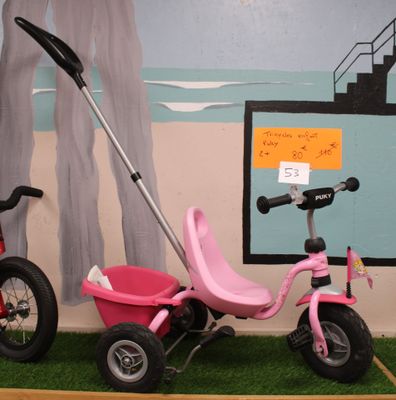 a pink tricycle and a pink tricycle in a room