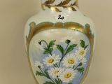 a white vase with flowers painted on it on a table