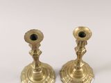 two gold candlesticks sitting on a white surface