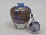a glass vase with a spoon next to it on a table