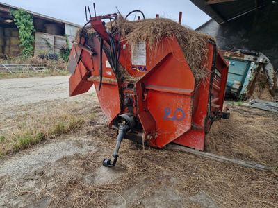 un tracteur garé à côté d'un tas de foin