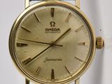 une montre en or avec un bracelet noir sur fond blanc