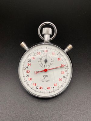 un chronomètre argenté avec une trotteuse rouge sur un fond noir