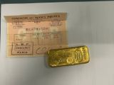 a gold bar next to a receipt on a table