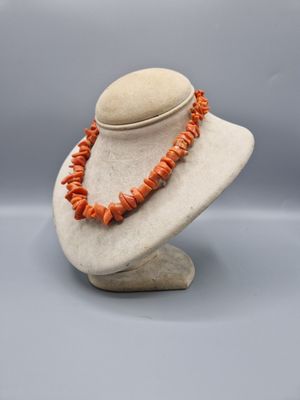 un mannequin blanc orné de perles de corail orange