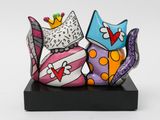 two colorful cats sitting on top of each other on a black stand