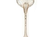 une cuillère ancienne en argent sur fond blanc, ornée d'un motif floral
