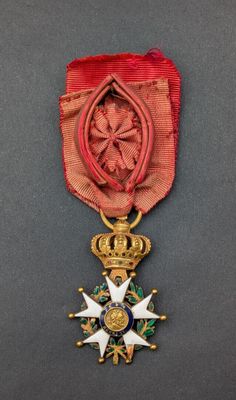 un gros plan d'une médaille ornée d'un ruban rouge sur fond gris