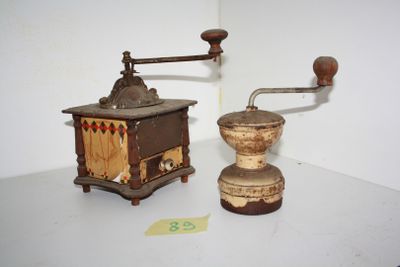 two old coffee grinders sitting on a white table