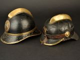 pair of black and gold fireman ' s helmets on a black background