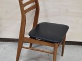 a wooden chair that has a black seat on it