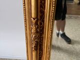 a mirror that has a gold frame with a lion head on it