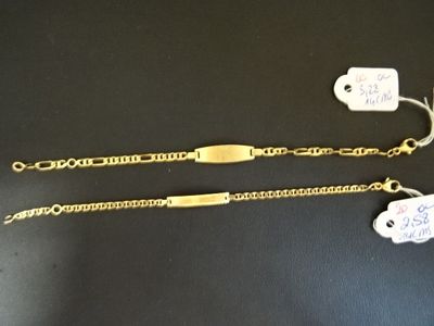 deux chaînes en or auxquelles sont attachées des étiquettes, posées sur une table