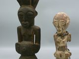 Deux figurines africaines sont assises l'une à côté de l'autre sur une surface blanche
