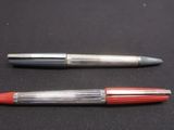 two pens that are sitting on a black surface