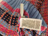 a close up of a knitted scarf with a tag attached to it