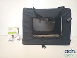 a small black dog in a pet carrier next to a box
