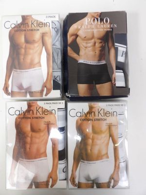 Trois sous-vêtements pour hommes sont posés sur une table devant un livre