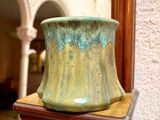 un vase vert posé sur une étagère en bois